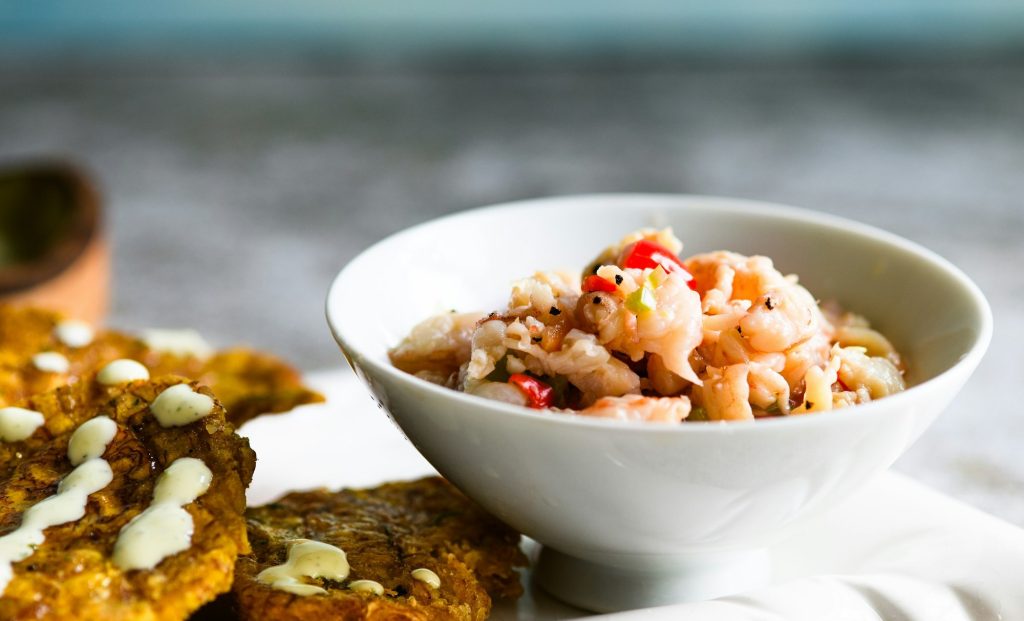 Ceviche de camarón servido en un cuenco blanco con patacones