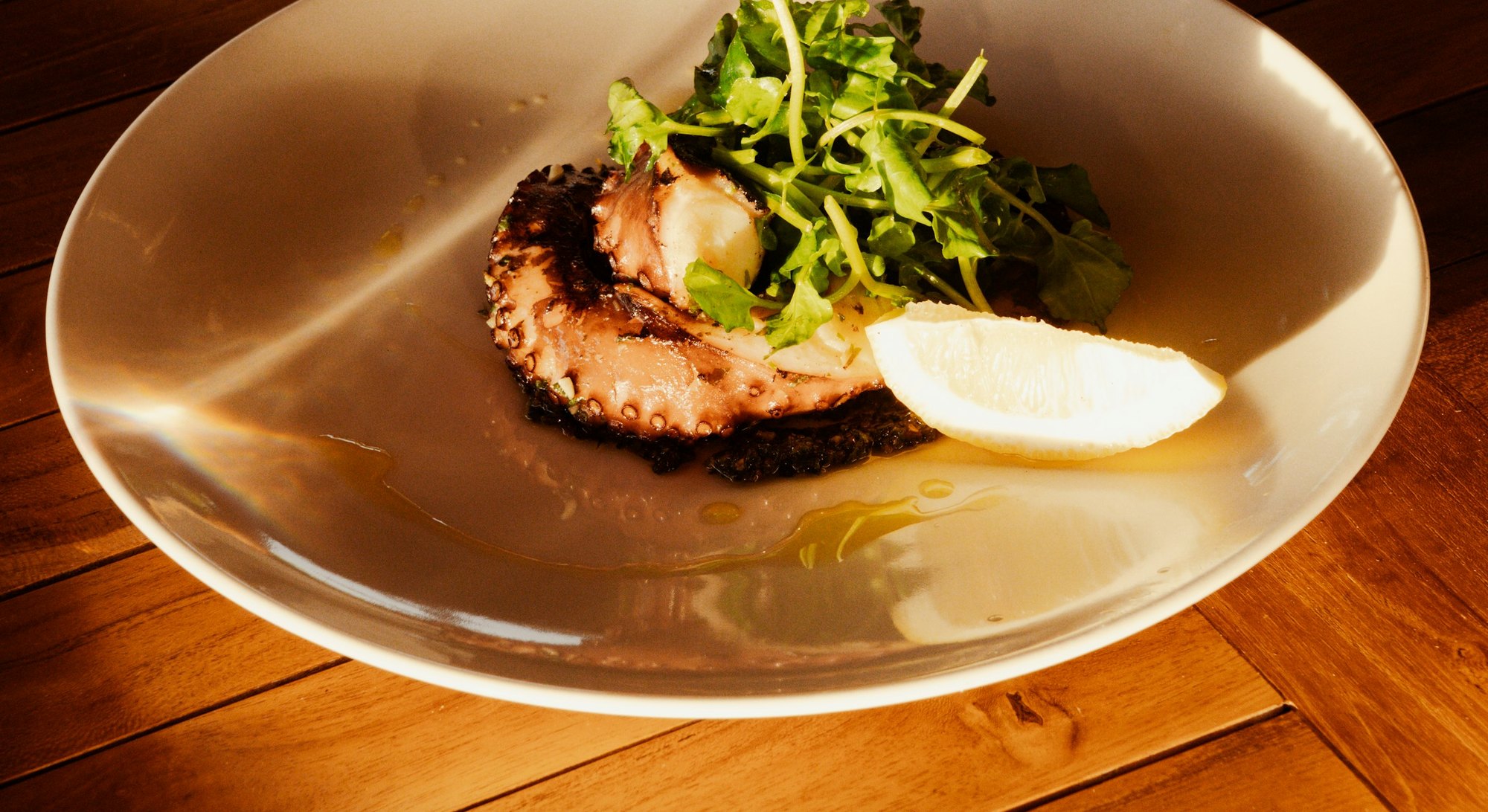 Pulpo a la brasa emplatado con hierbas frescas y limón