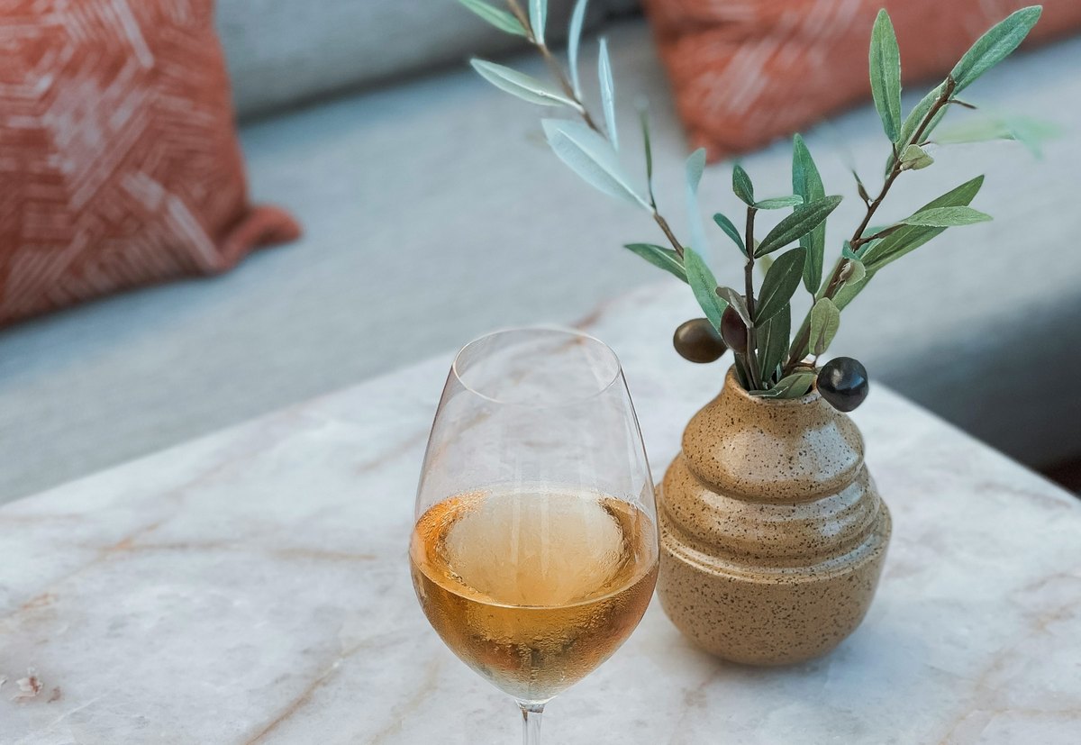 Copa de vino sobre una mesa de mármol con una rama de olivo y luz natural